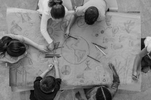 An aerial view of a multi ethnic group of children learn about going green and color in environmentally friendly concepts surrounding a drawing of Earth.