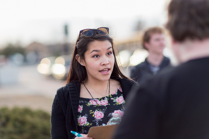 Canvasser with clipboard talking to man